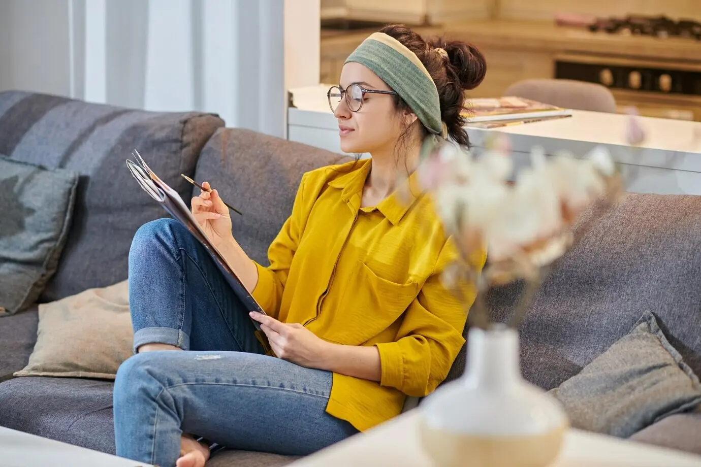 Im Atelier sitzt ein/e junge/r Maler/in mit inspiriertem Blick.